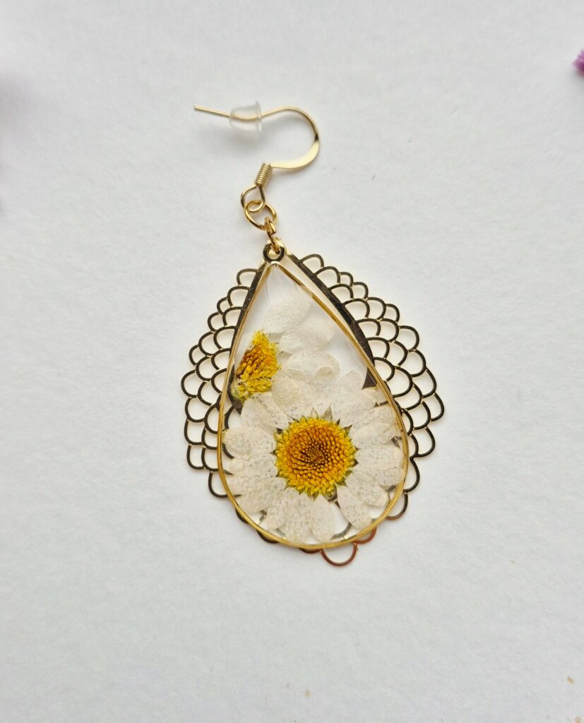 Boucle d'oreille goutte en résine avec une marguerite séchée, entourage doré ajouré