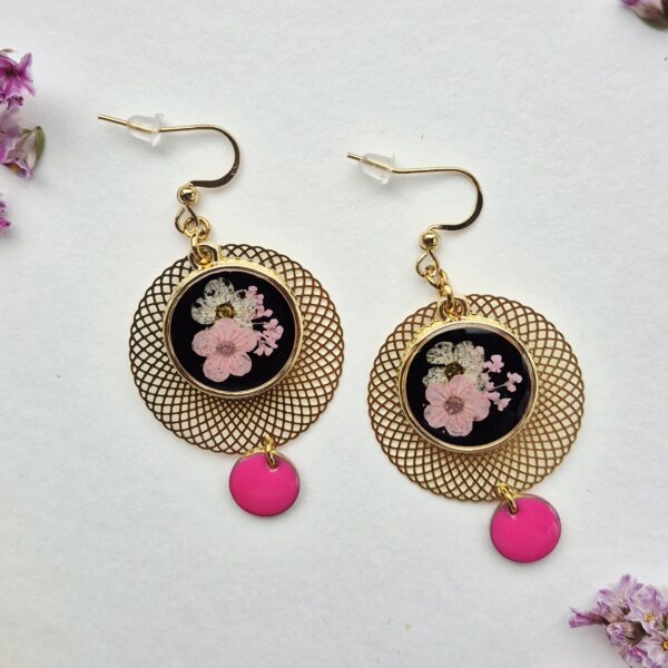 Paire de boucles d'oreilles en résine, bouquet de fleurs roses et blanches sur fond noir, rosace dorée et pastille rose fuchsia