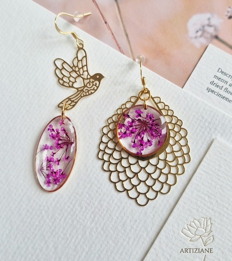 Boucles d'oreilles dépareillées en résine aux fleurs violettes séchées, avec un oiseau et une estampe dorés