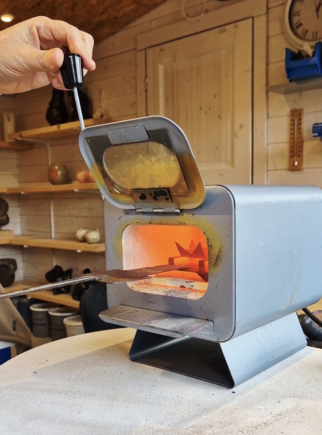 Pièce de cuivre émaillée déposée à la pince dans le four rougeoyant de l'atelier