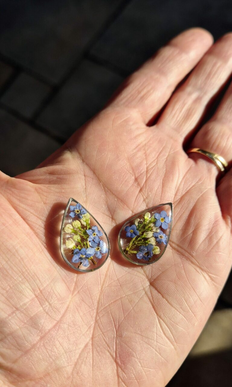 Boucles d'oreilles en résine aux fleurs bleues et jaunes tenues dans la main